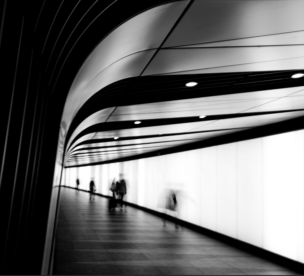 Blurred black and white portrait of people walking through a subway