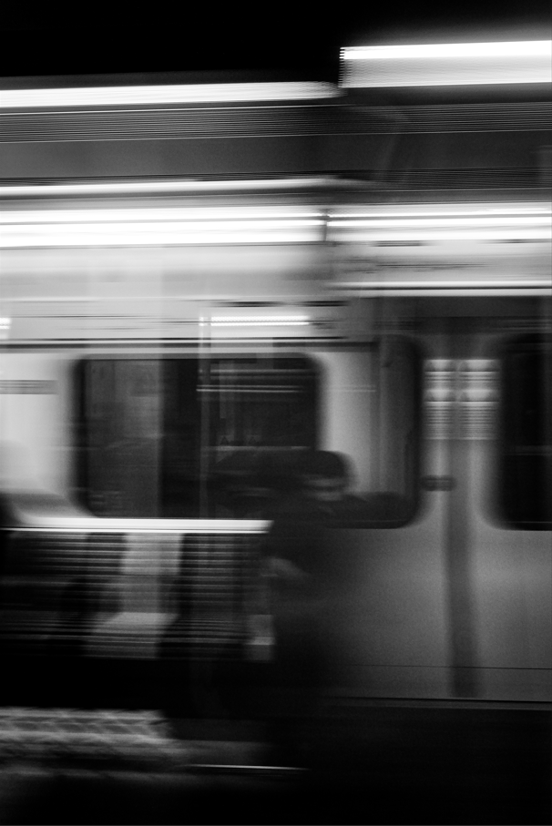 blurred photo of man sitting and reading on the subway 