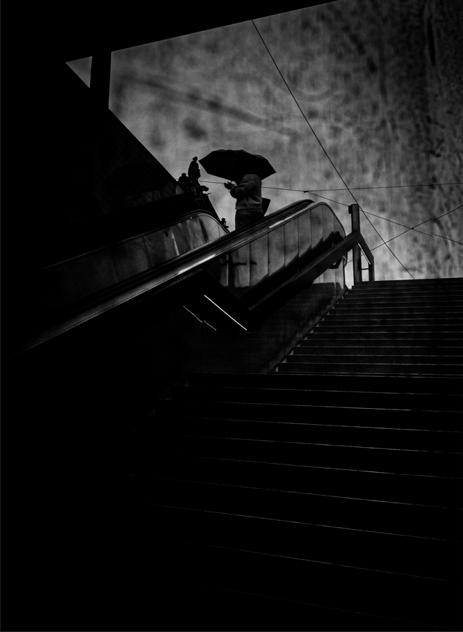 black and white artwork of woman standing at the top of stairs holding an umbrella 