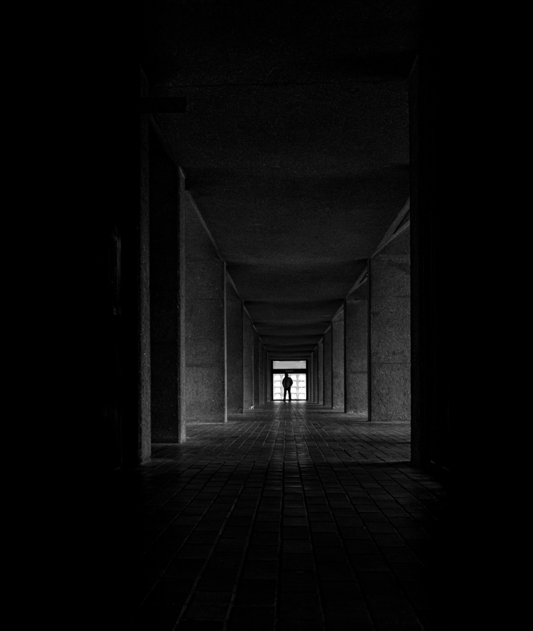 Long, dark hallway with a person standing at the end